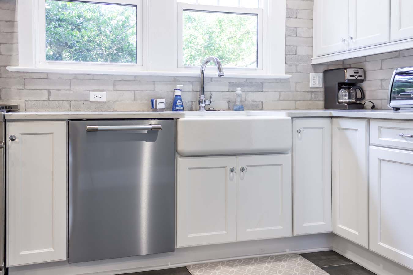 A kitchen with Kohler sink faucet and a white farmhouse sink.